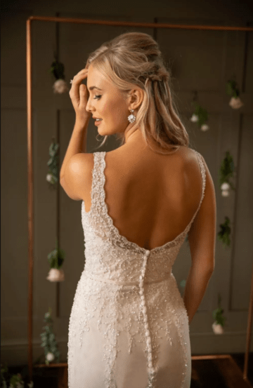 This is a picture of a wedding dress called Lucille by designers True Bride. For the Bride who is looking for a contemporary look with a classic silhouette, this chic style has a flattering deep v-neckline handcrafted with free beaded and embroidery on the softest of tulle. The bodice is encrusted with pearls and crystals on embroidery that continue down the skirt from the waist. Available from Fairytale Bride.